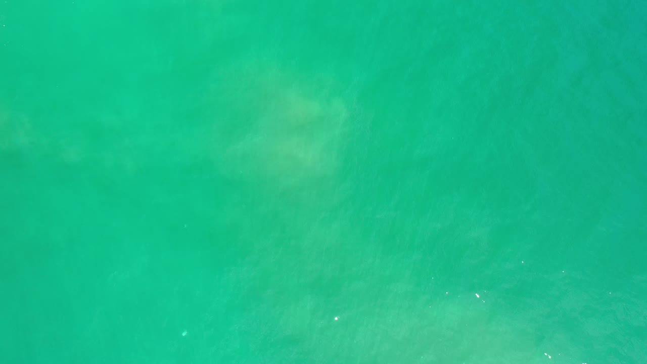 Green ocean surface in Los Cabos, Mexico, with diffuse underwater wave shapes and no visible people.