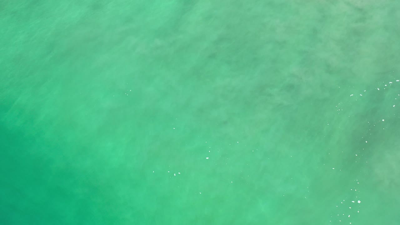 Opening overhead view of turquoise and green sea water in Los Cabos, Mexico, with faint ripples, pale underwater texture, and no visible people.