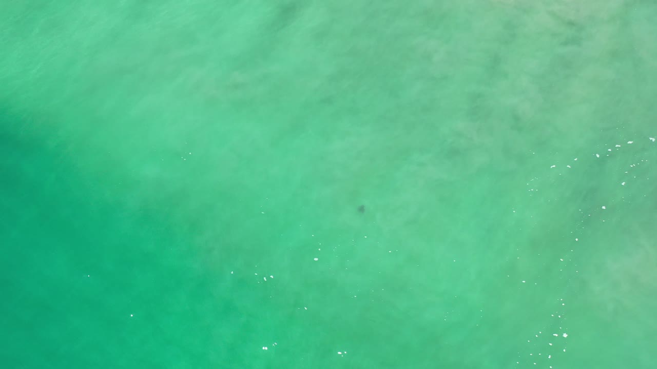 Aerial view of turquoise sea with diagonal sparkle marks.