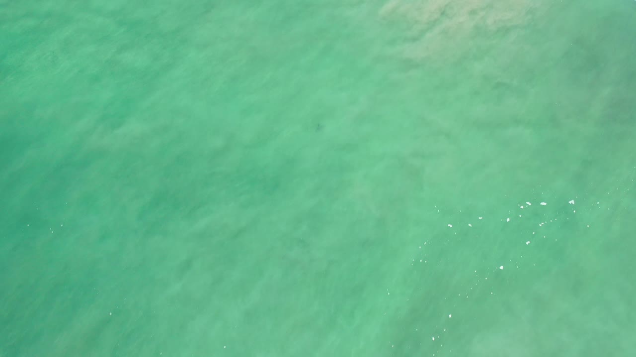 Turquoise sea surface with faint darker streaks under the water.
