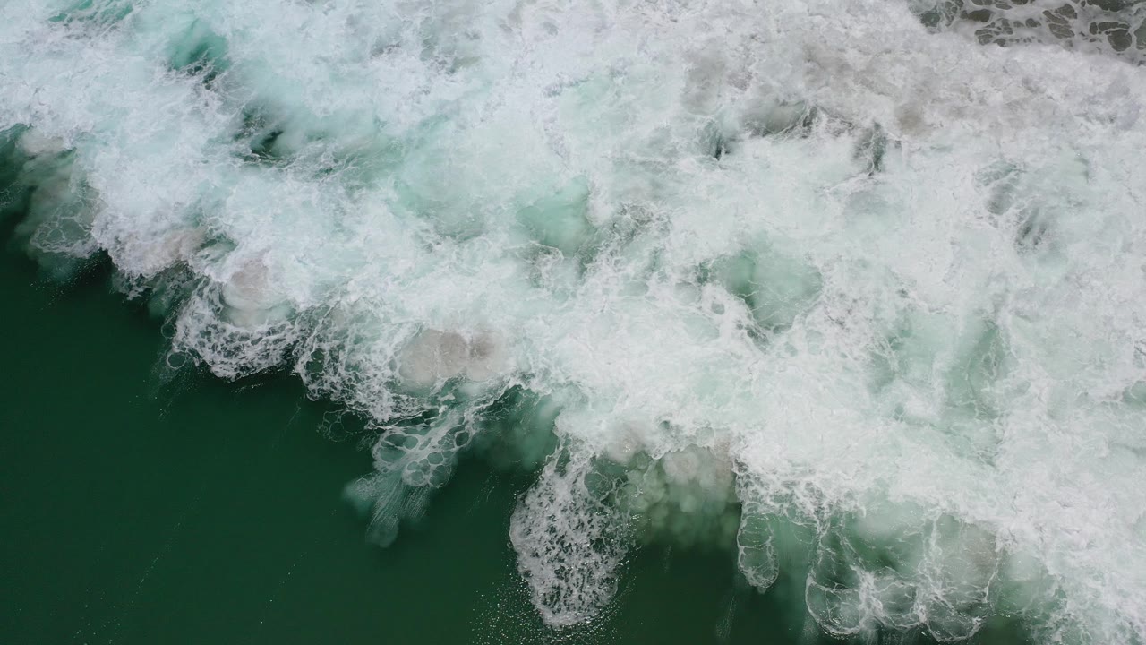 Overhead white surf foam over dark green ocean water.