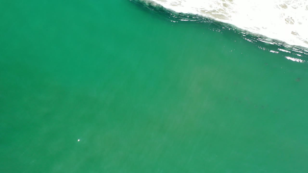 Overhead green-blue water with surf foam at the top edge.