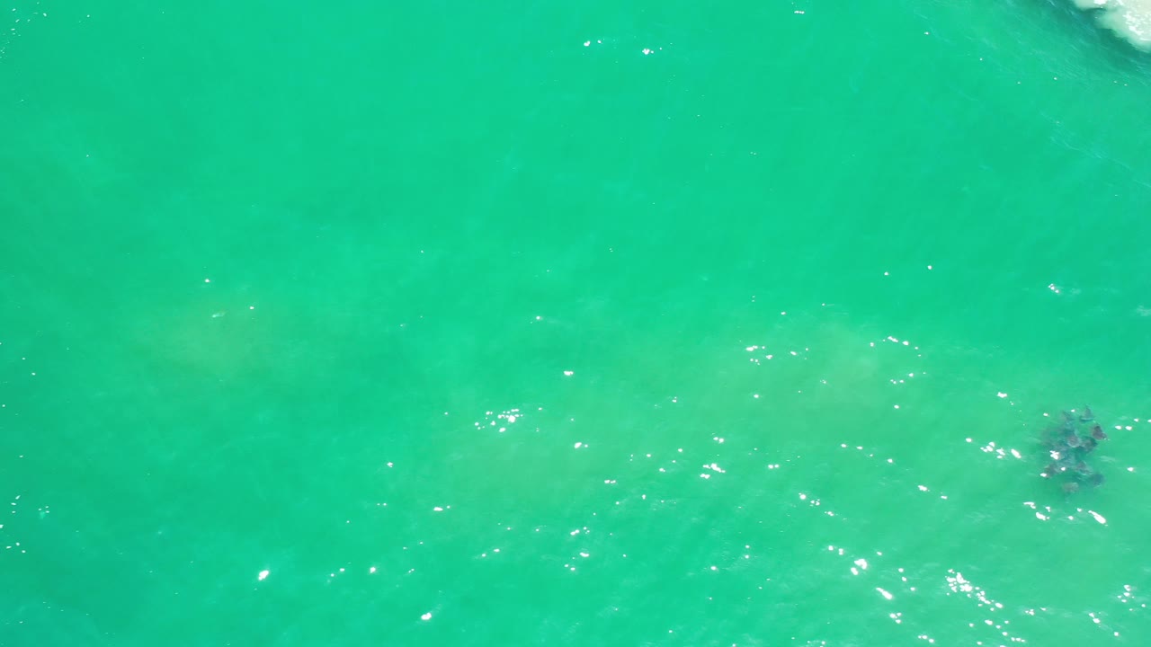 Turquoise ocean seen from above with small foam at the frame edge.