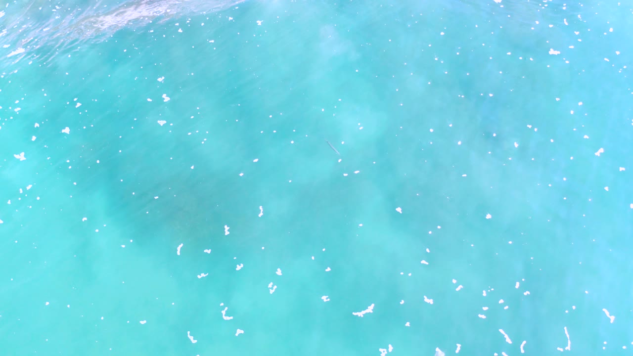 Overhead view of turquoise ocean water in Los Cabos, Mexico, with bright surface specks and no visible people.