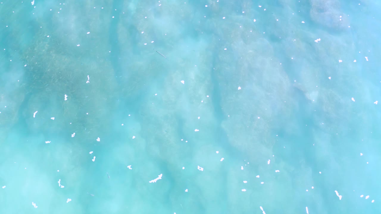 Overhead Los Cabos water frame showing pale cloudy seabed patterns beneath the turquoise surface and no visible people.