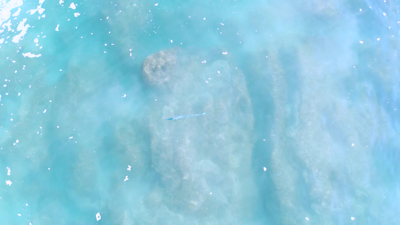 Turquoise water in Los Cabos, Mexico, shows pale submerged contours, scattered white highlights across the surface, and no visible people.