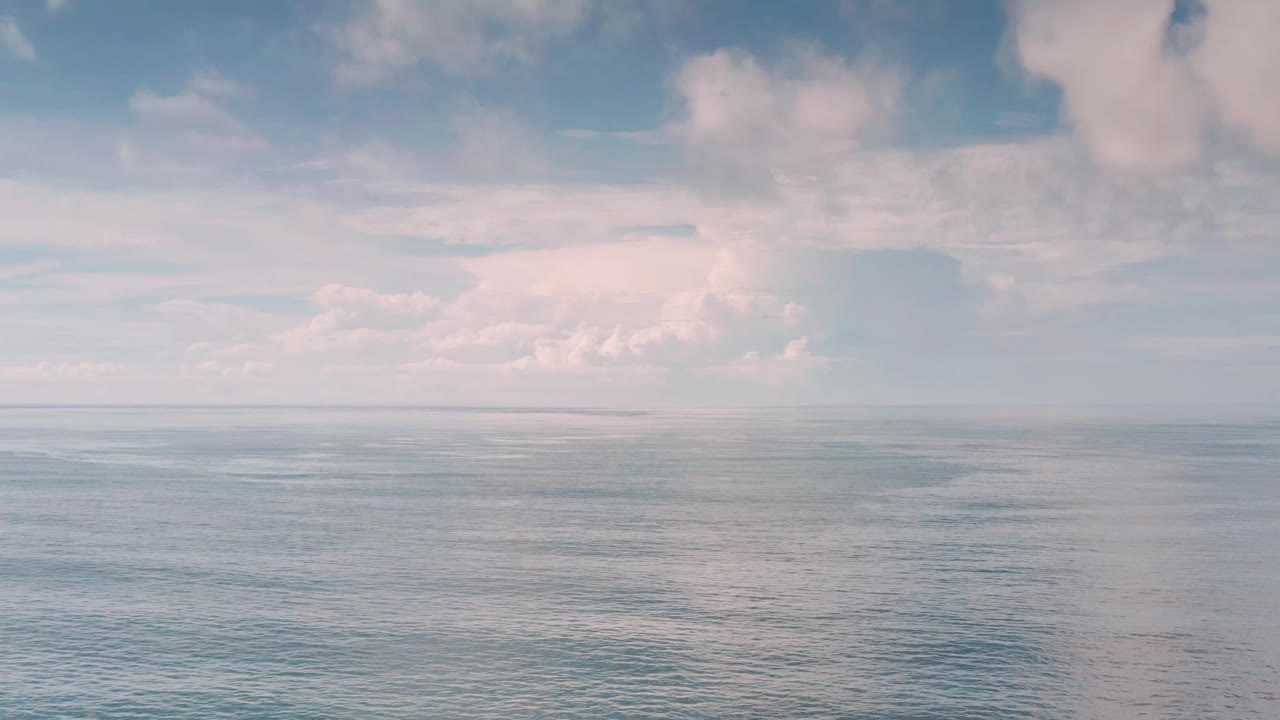 A second moment holds the Los Cabos horizon line steady, with rippled ocean surface in the lower half and layered soft clouds above, no visible people.