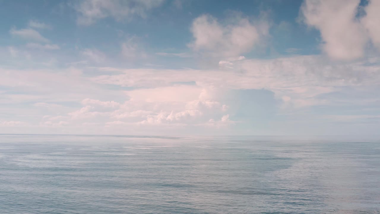 A muted blue ocean surface stretches toward the horizon in Los Cabos, with layered clouds above and no visible people, boats, or buildings.