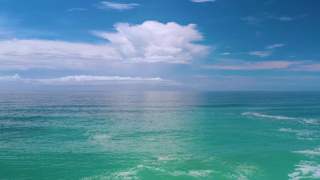 Calm ocean surface with white cloud bands along the horizon