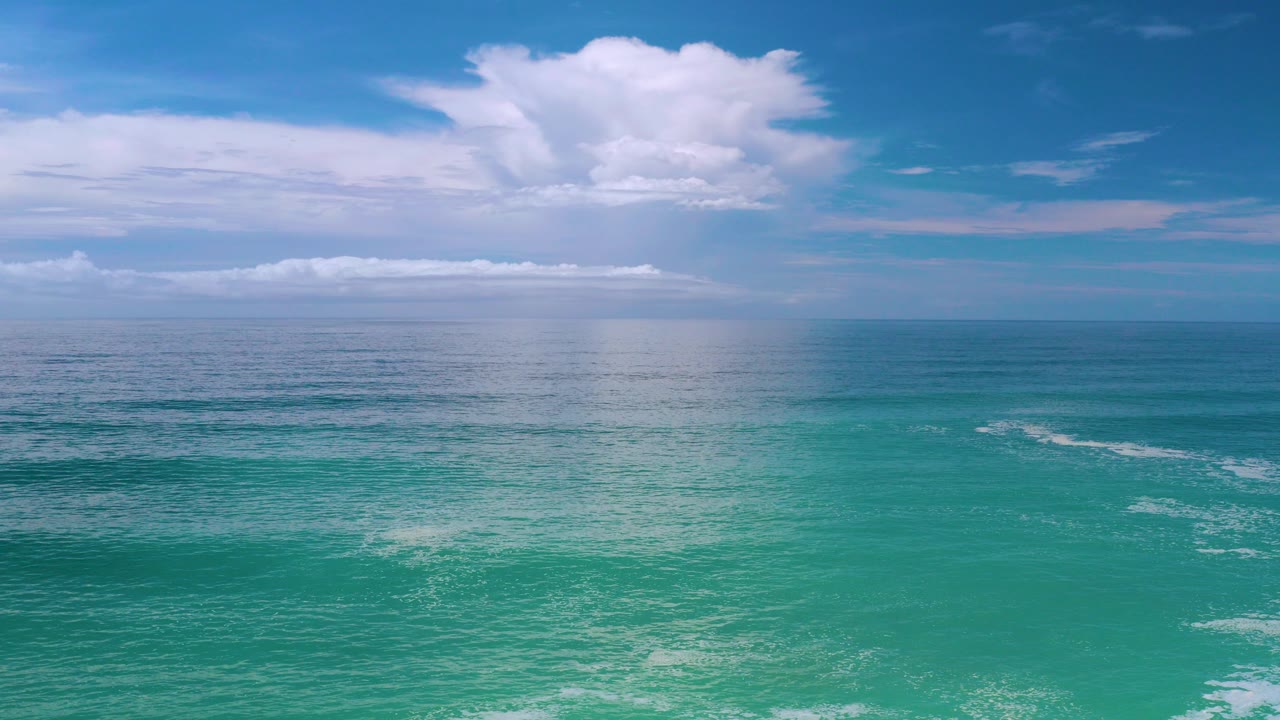 Los Cabos ocean view with turquoise water, a high horizon, broad white clouds, and no visible people at the start of the clip.