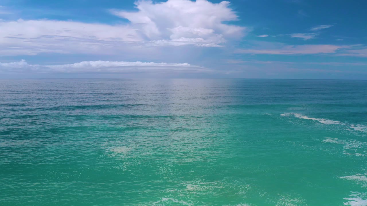 Blue-green ocean with bright cloud reflection near the horizon.