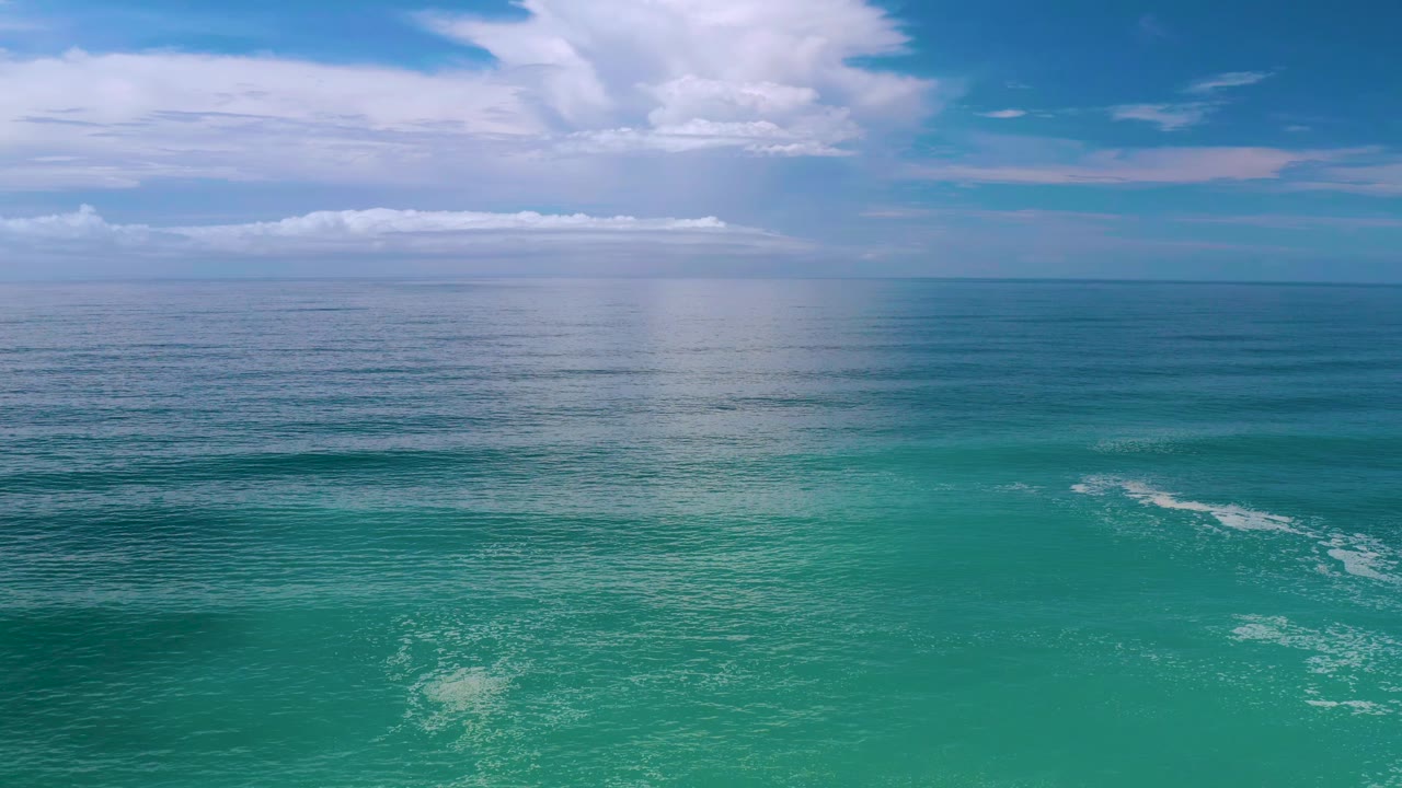 Los Cabos, Mexico coastal water with a pale cloud reflection centered on the sea, a blue horizon line, and no visible people.