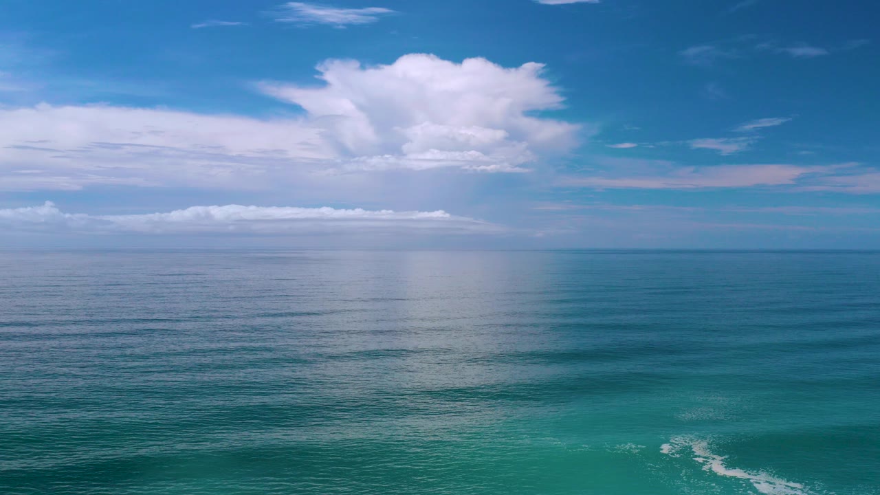Los Cabos ocean horizon under a deep blue sky with broad white clouds and no visible people at the opening moment.
