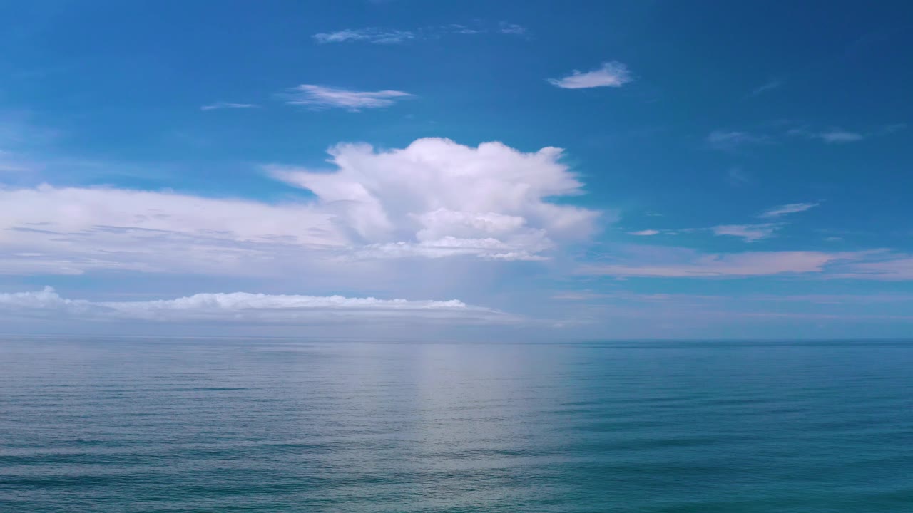 Wide Los Cabos ocean view with layered clouds stretching along the horizon and a larger cloud mass rising above them, with no visible people.