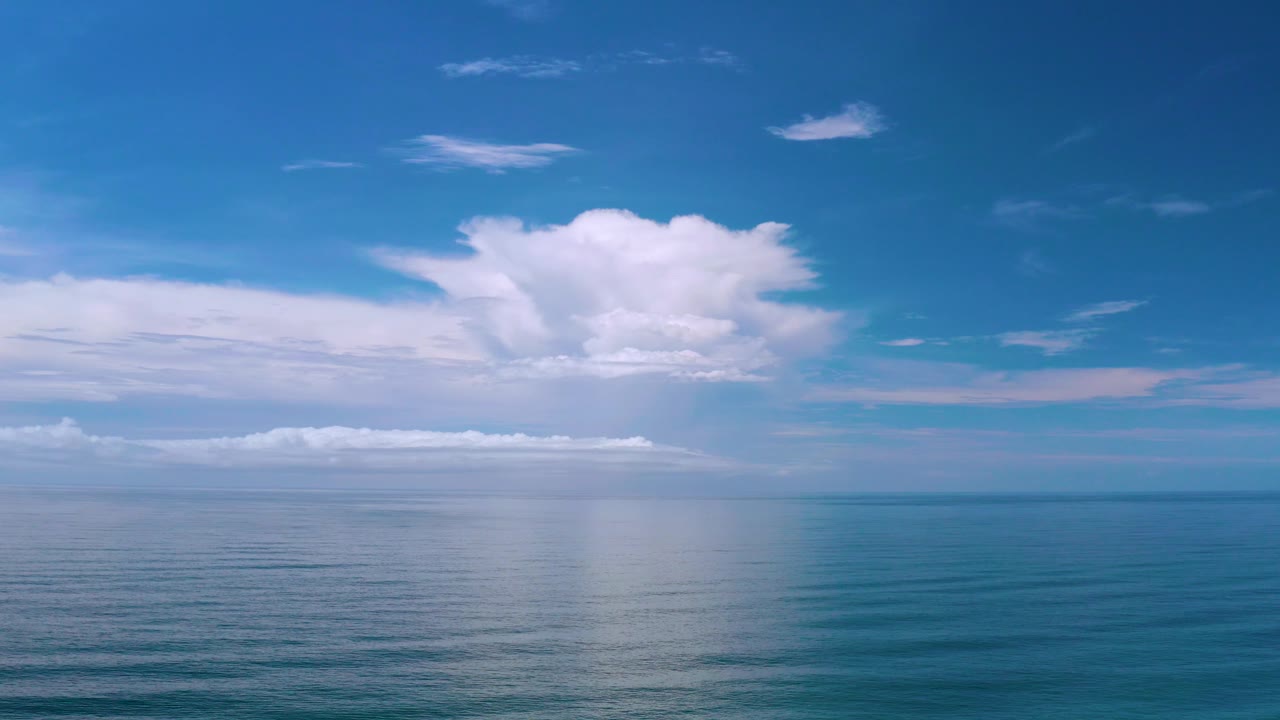 Mid-clip Los Cabos frame with the horizon low in the composition, a bright cloud formation overhead, and no visible people or vessels.