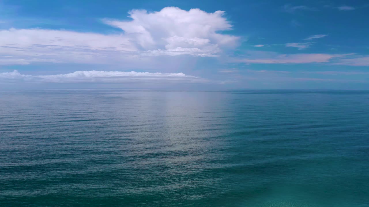 Los Cabos, Mexico water view with the cloud reflection centered on the ocean surface, a thin horizon line, blue sky above, and no visible people.