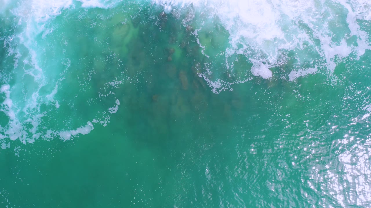 Turquoise ocean surface with white foam and bright reflected light.