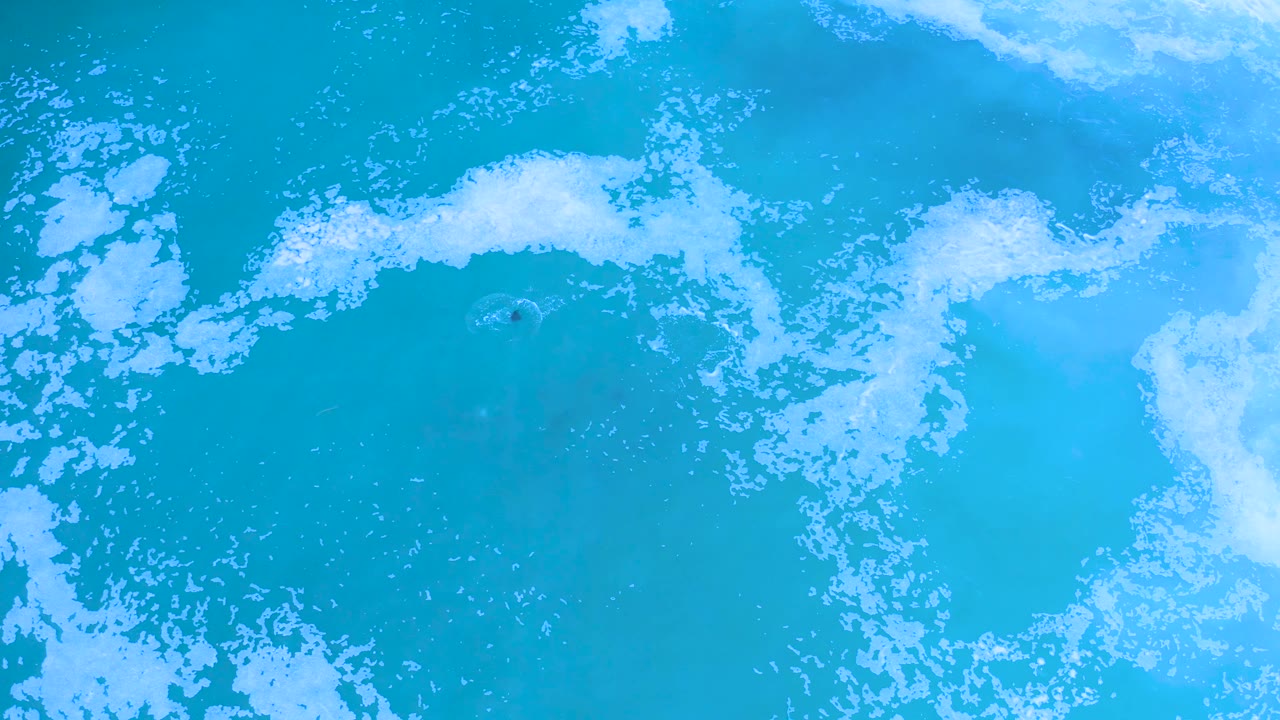 Turquoise sea surface with broad white foam patches