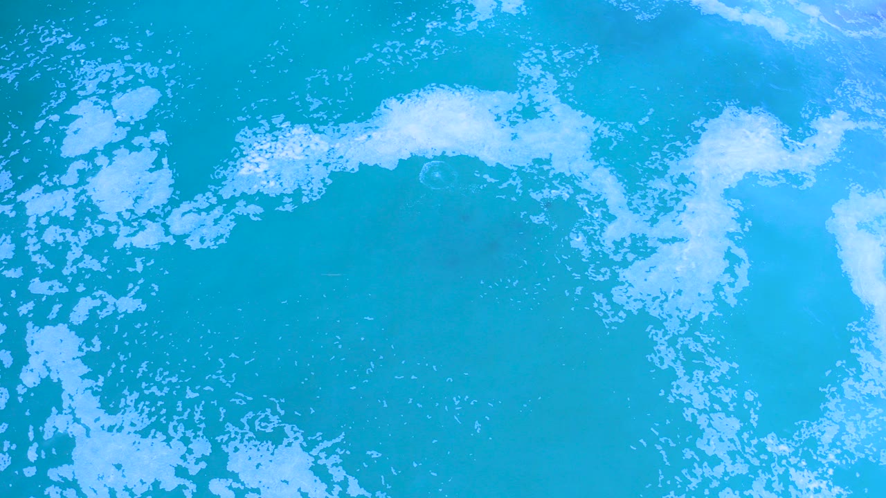Turquoise ocean surface with white foam across the top edge.