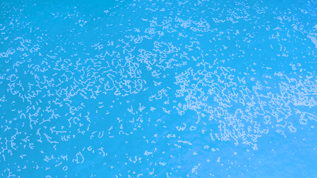 Turquoise sea surface in Los Cabos, Mexico, with bright white rippled texture running across the upper and central areas and no visible people.