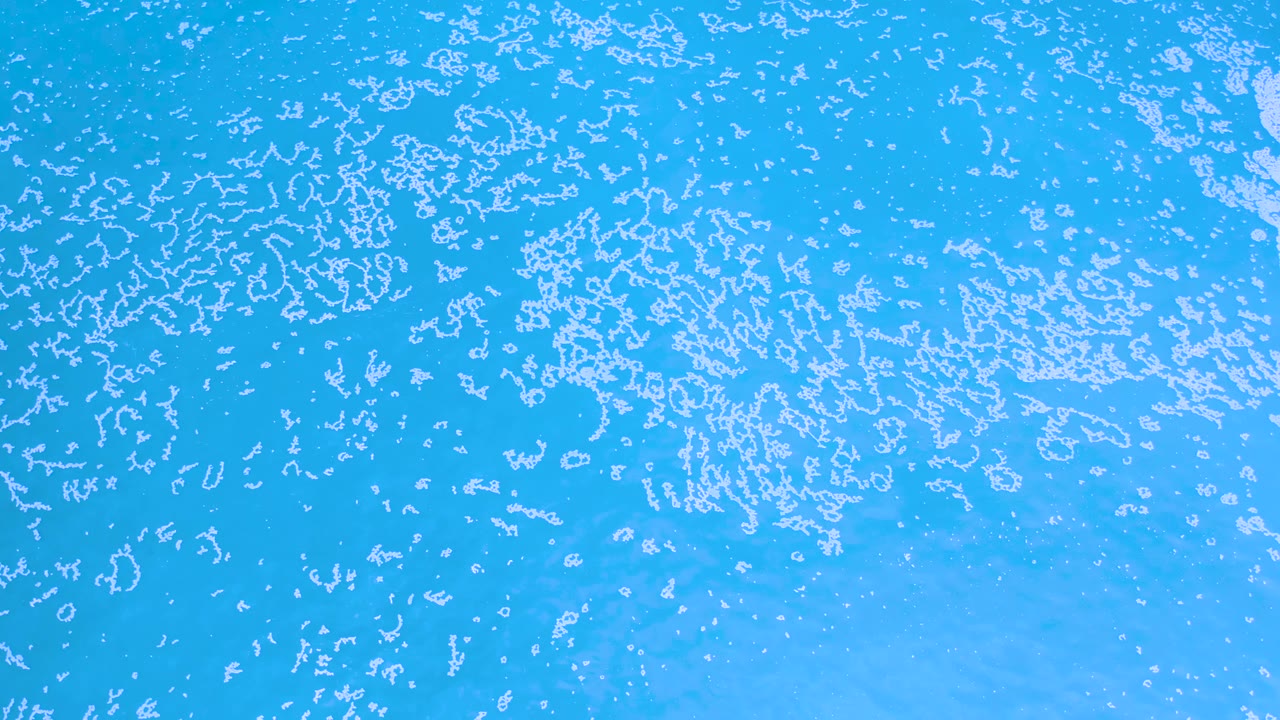 Los Cabos ocean surface with dense white flecks across the upper area, lighter blue water below, and no visible people.
