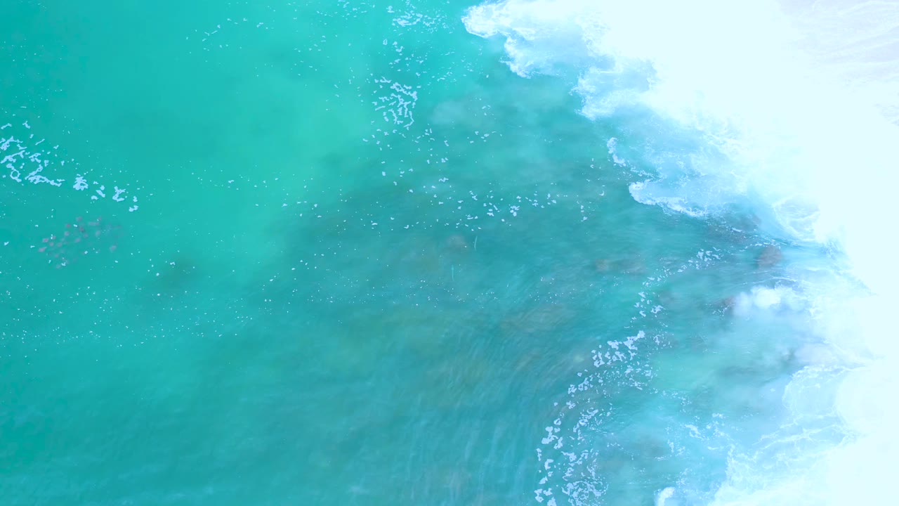 Overhead view of turquoise water and white surf along the right side of the Los Cabos coastline, with no visible people.