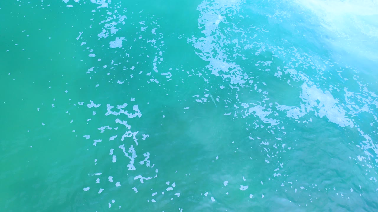 Turquoise ocean water with white foam bubbles.