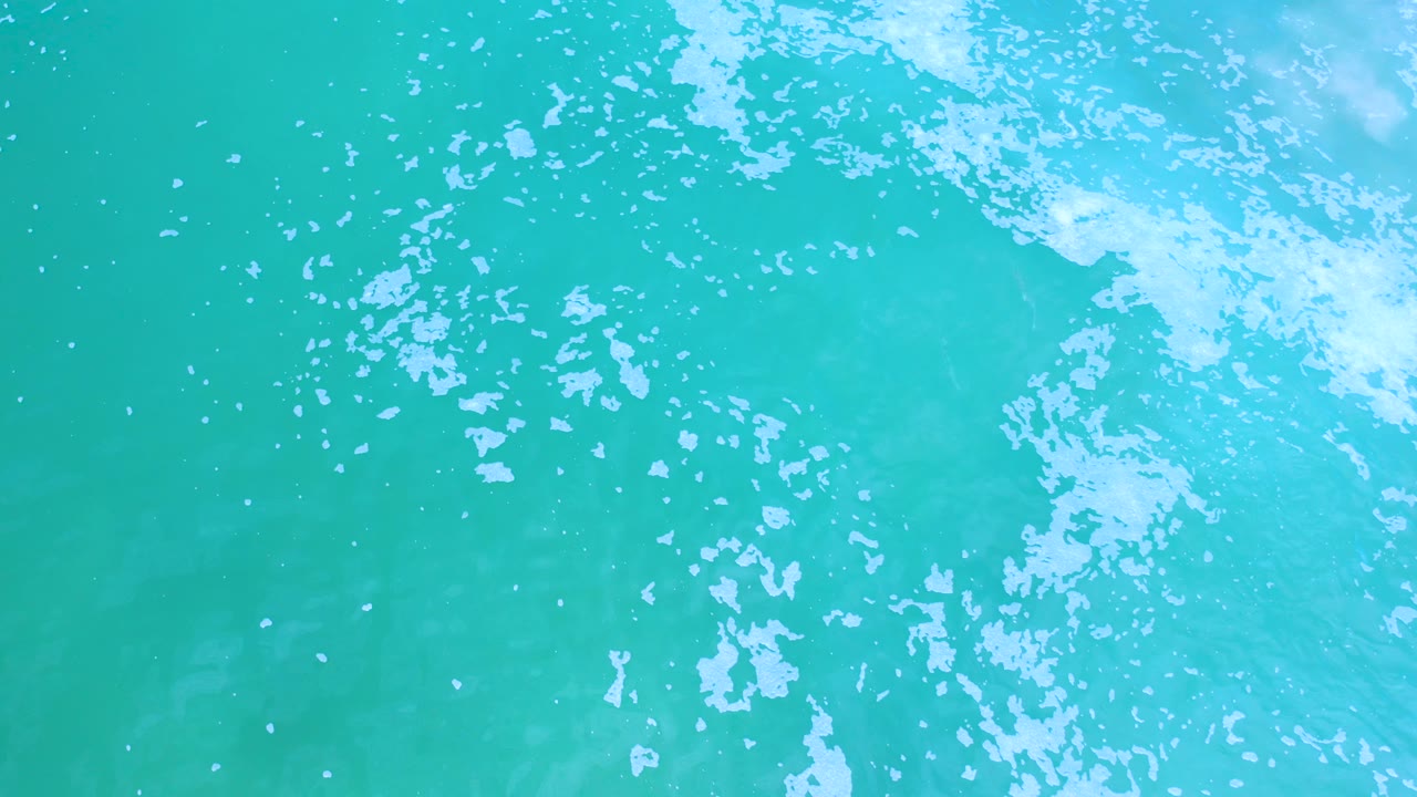 Blue-green water with a pale foam band crossing the frame.
