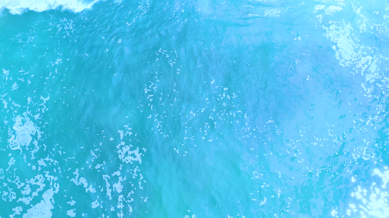 Turquoise water with white foam and bright surface highlights.