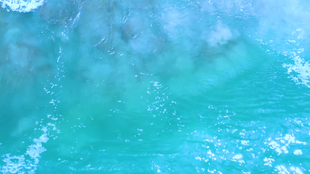 Overhead Los Cabos seawater fills the frame, with pale ripples, a small foam patch near the top, and no visible people.