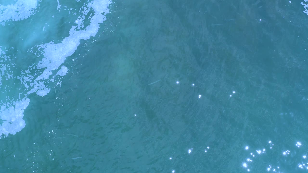 Ocean water seen from above with foam along the upper edge