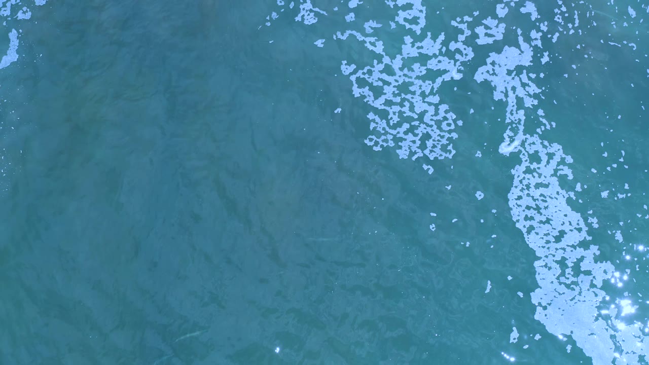 Overhead Los Cabos ocean frame with white froth running vertically through blue-green water and no visible people or shoreline.