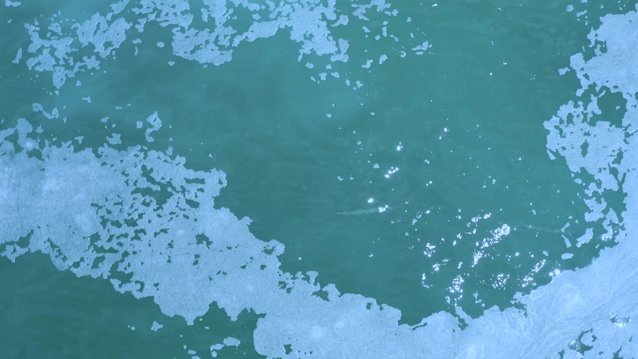 Ocean water with pale foam bands and scattered highlights.