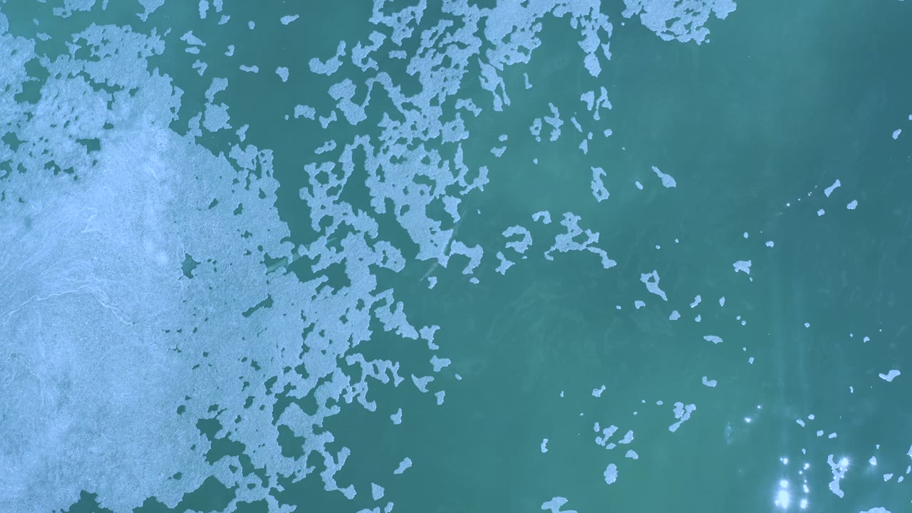 Foam field and teal water with bright glints