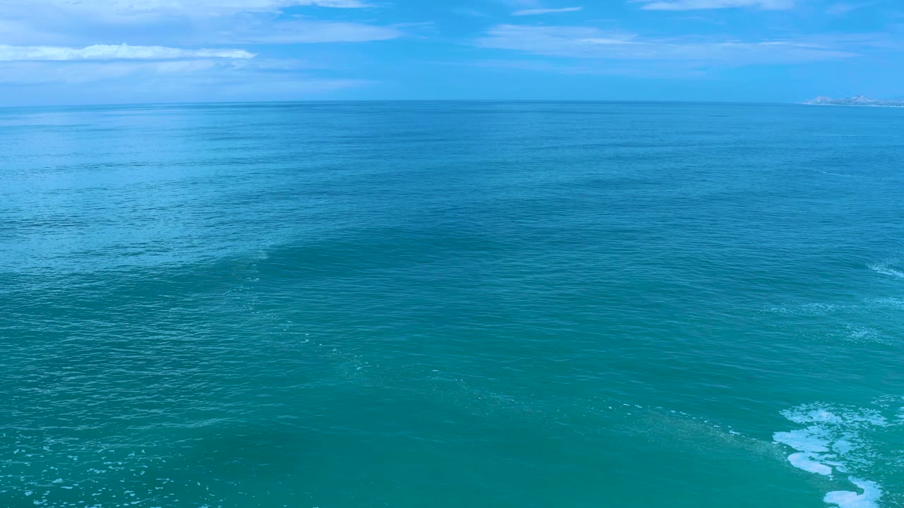 Open blue-green sea with faint wave texture and clouds above.
