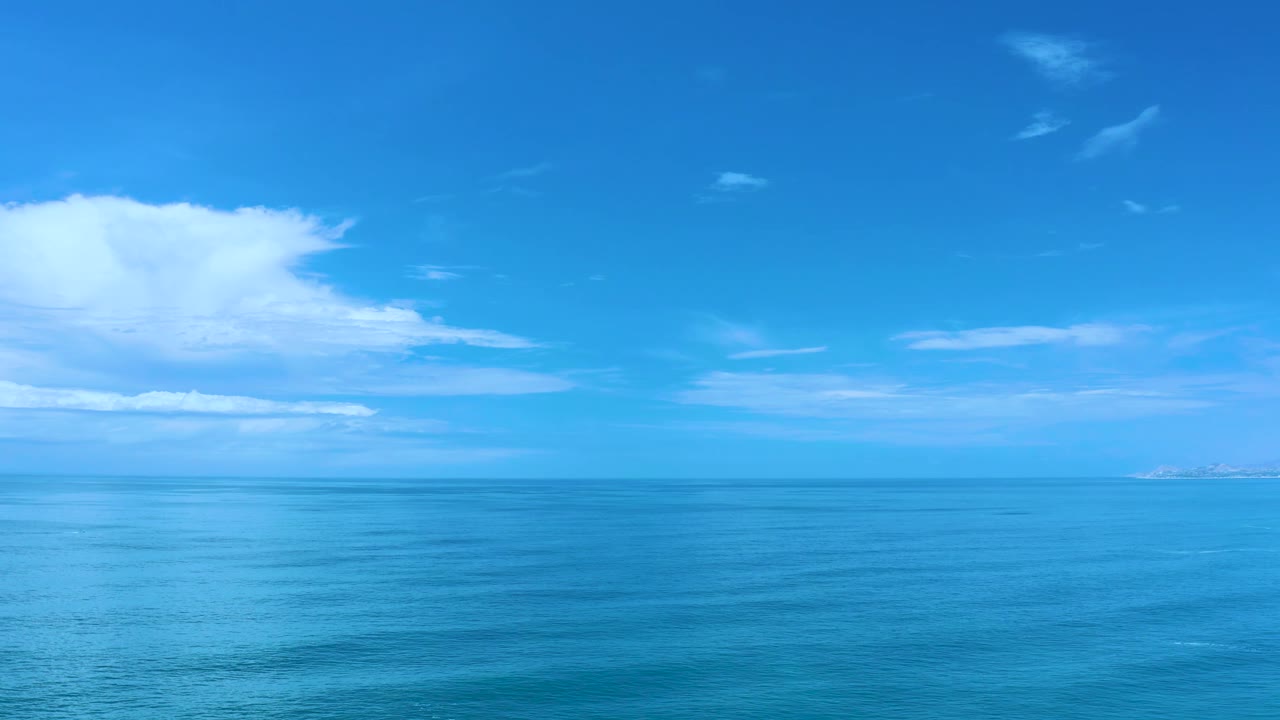 Blue ocean below a bright sky with clouds near the left side.