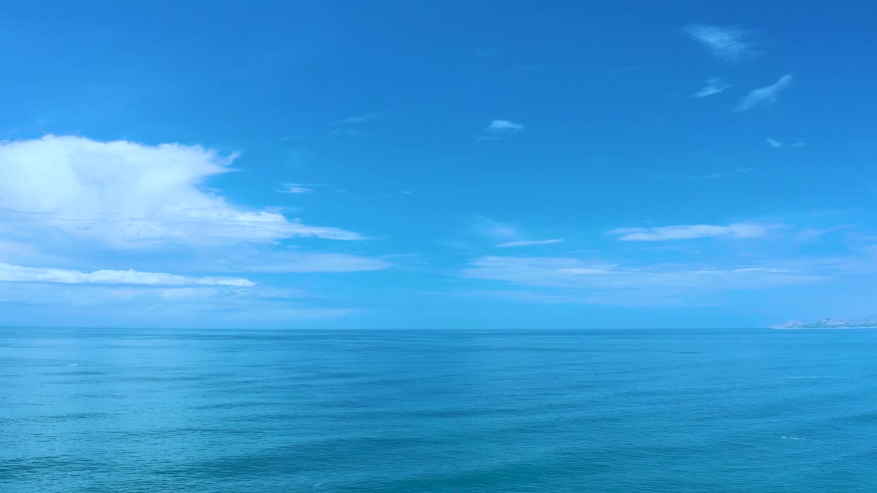 Blue water fills the lower frame while thin clouds stretch across the Los Cabos sky, with no visible people, boats, or structures.