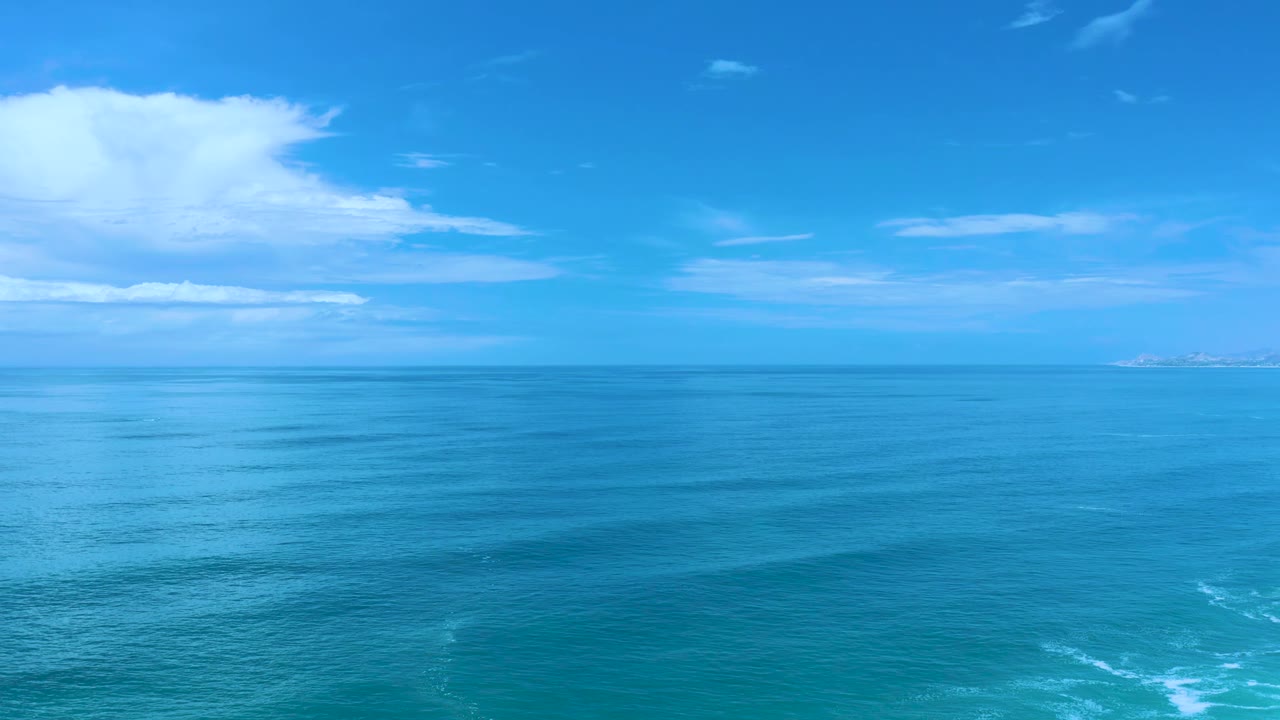 Blue water stretches to the horizon with faint surf below.