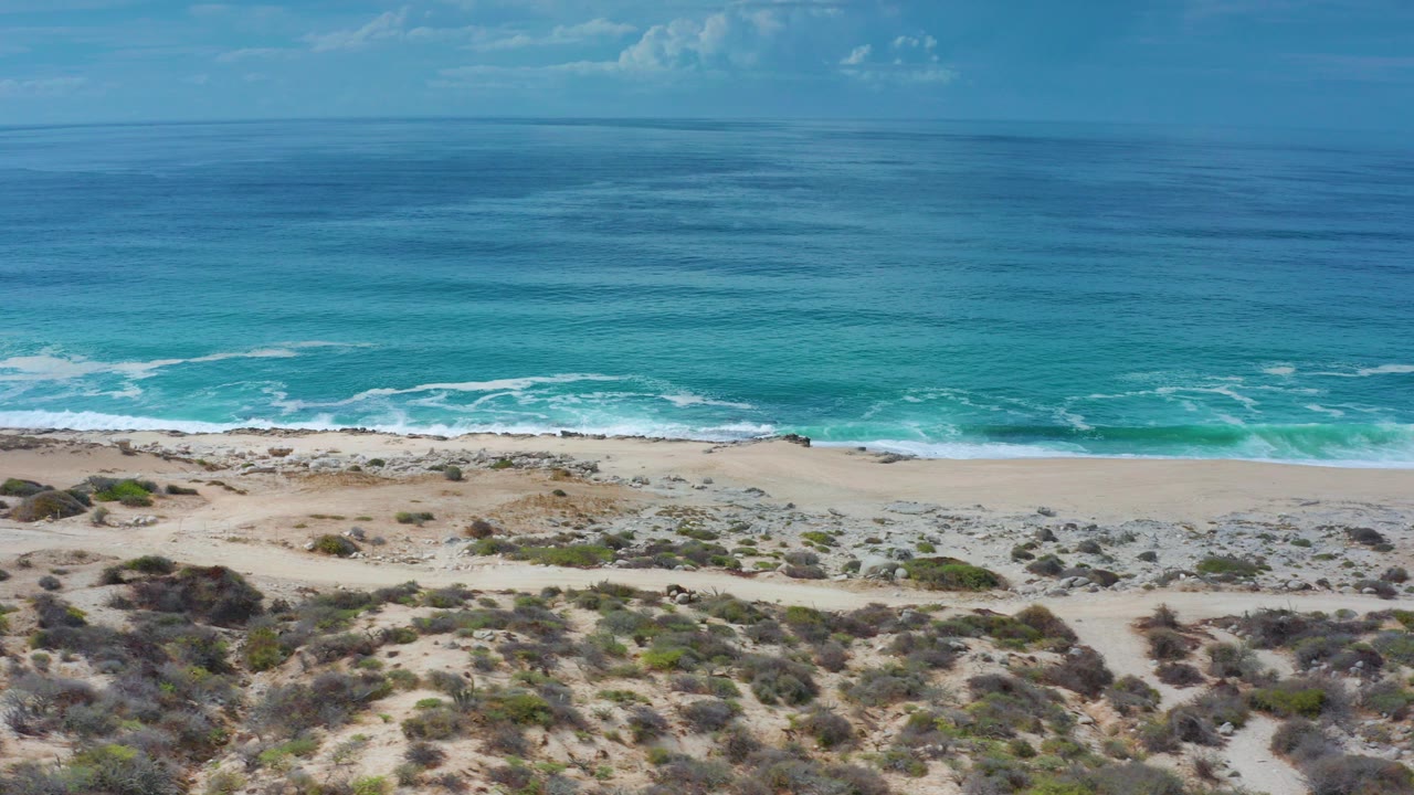 Blue ocean beyond sandy dunes and surf