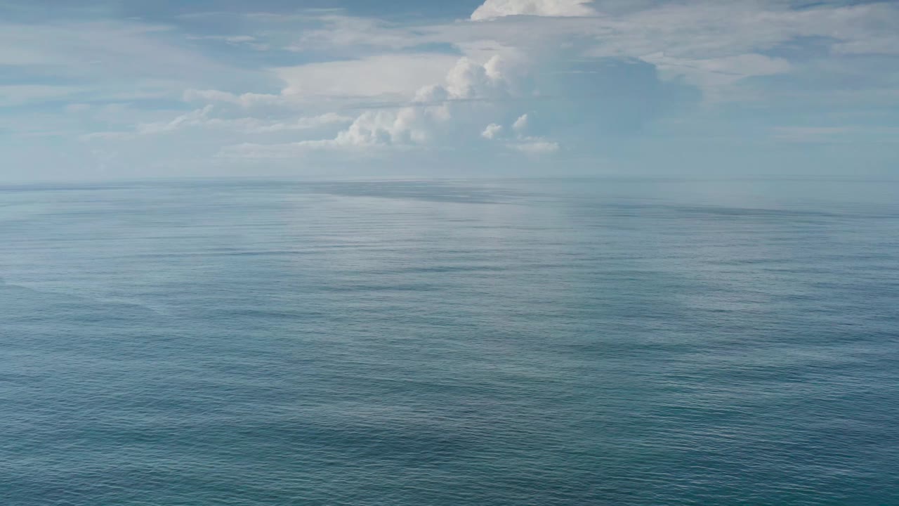 The Los Cabos sea fills most of the frame with subtle surface texture, a faint horizon, and high white clouds, with no visible people.