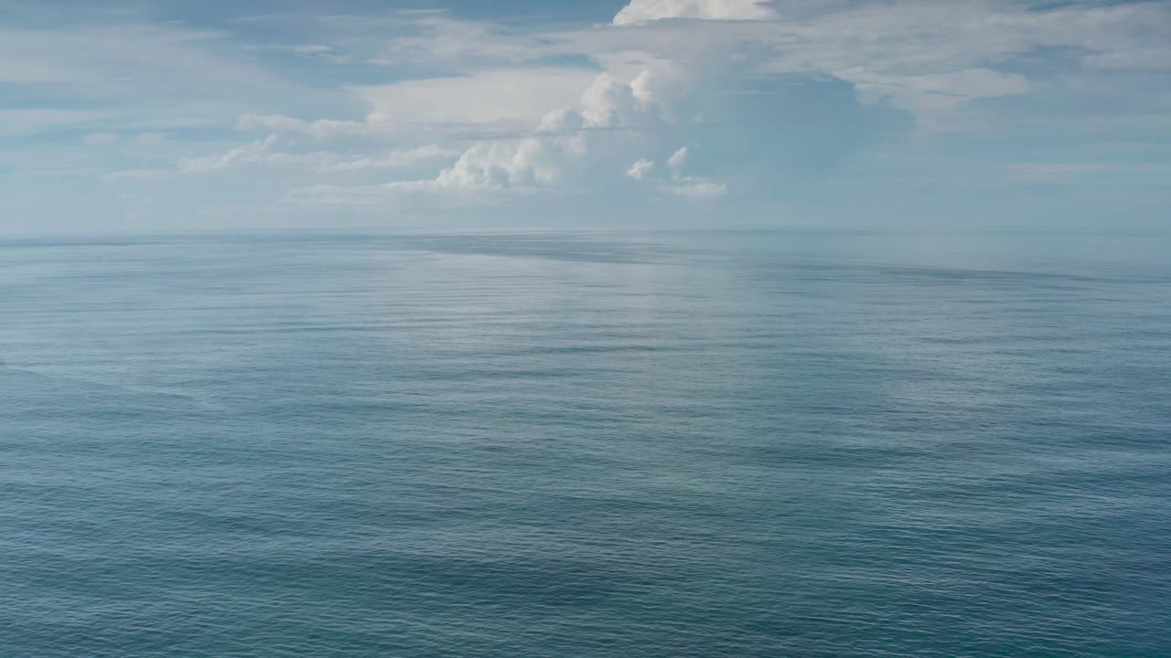 Wide ocean view with low horizon haze and bright clouds