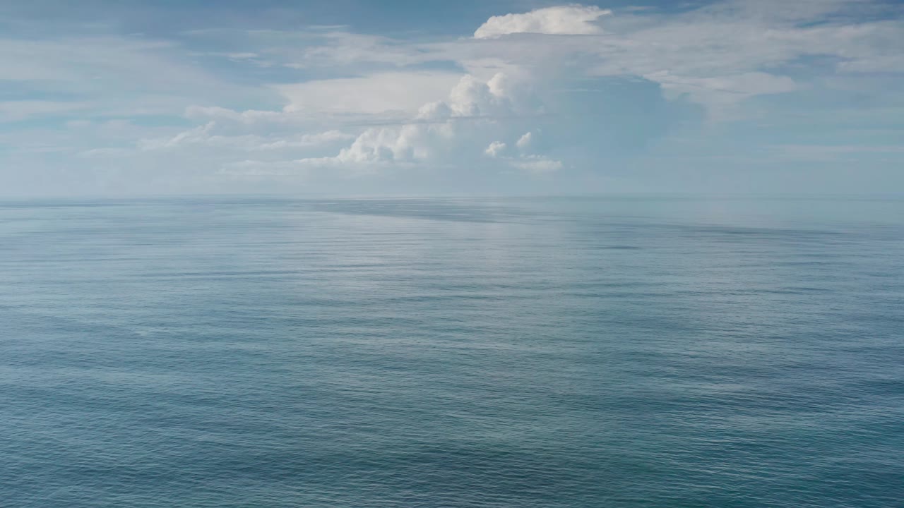 Los Cabos sea surface stretches to a level horizon beneath layered white clouds, with no visible people or vessels.