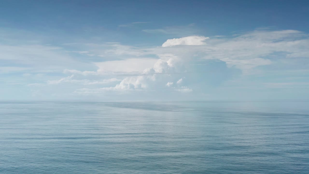 Early frame showing open blue ocean, a level horizon, and broad white cloud banks in Los Cabos, Mexico, with no visible people.