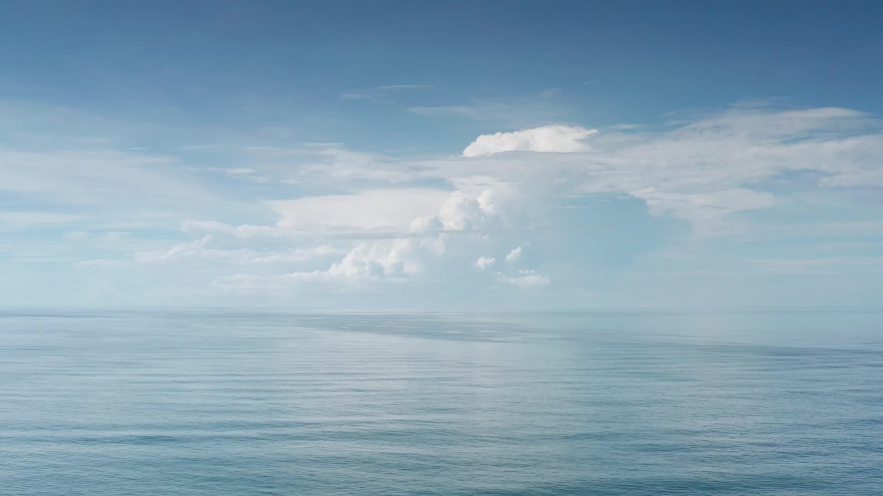 A wide Los Cabos seascape shows open water, a straight horizon, and white clouds spread across the sky with no visible people.