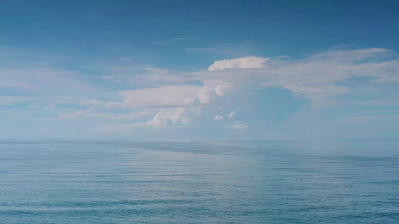 Opening frame of a Los Cabos, Mexico ocean horizon with calm blue water below layered white clouds and no visible people.