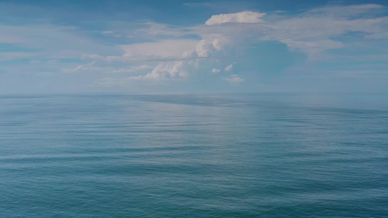 Los Cabos sea water fills the lower frame while a pale horizon and clustered clouds sit above it, with no visible people.