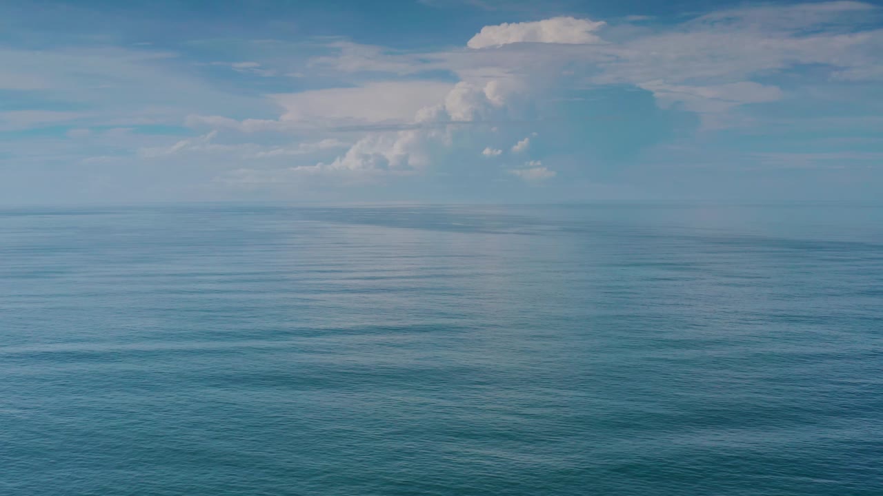 A broad Los Cabos ocean view shows subtle ripples across blue water beneath a soft cloud bank, with no visible people.
