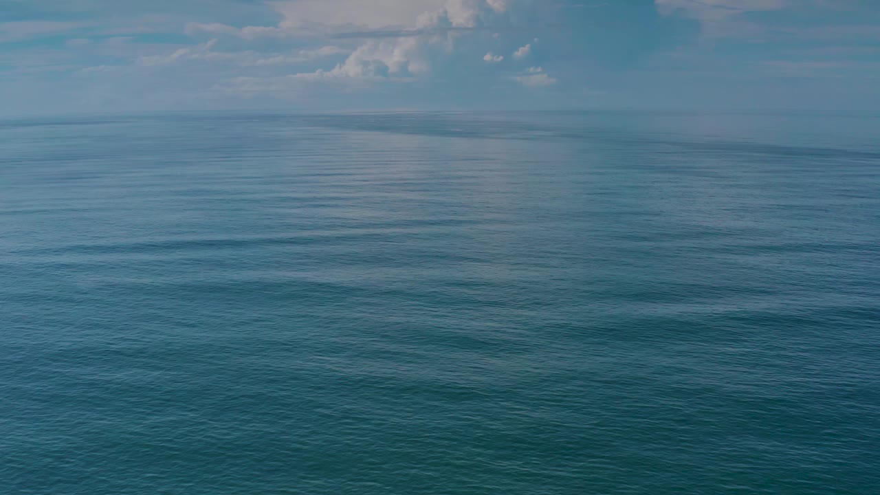 The Los Cabos seascape remains uncluttered, with blue water, a hazy distant horizon, small cloud forms, and no visible people.