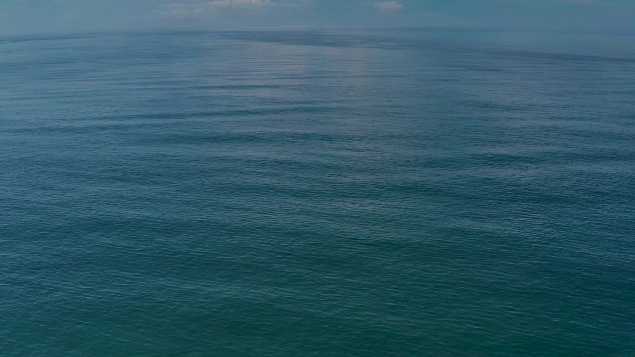 Los Cabos ocean water stretches toward a faint horizon, with subtle wave bands and no visible people.