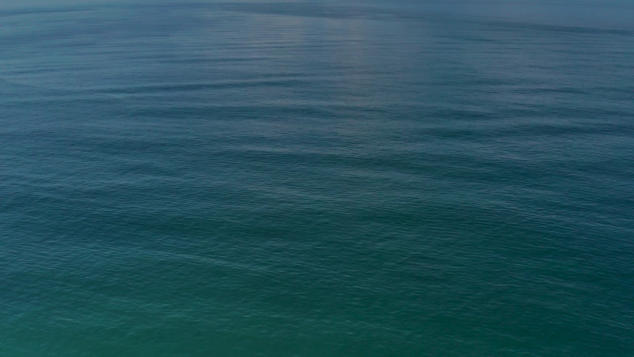 Blue-green ocean surface with small wave lines.